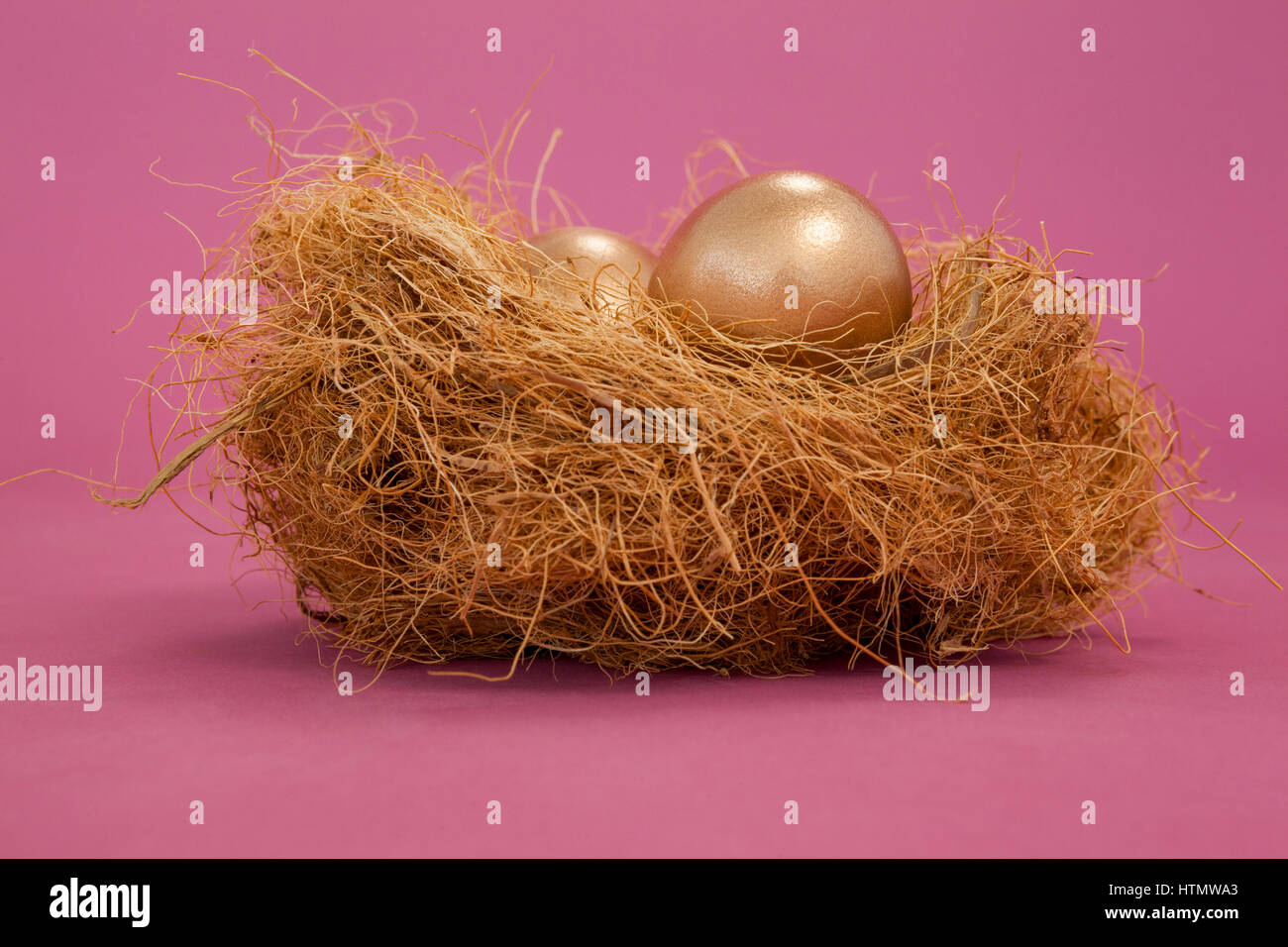 Golden Easter eggs in the nest on pink background Stock Photo - Alamy