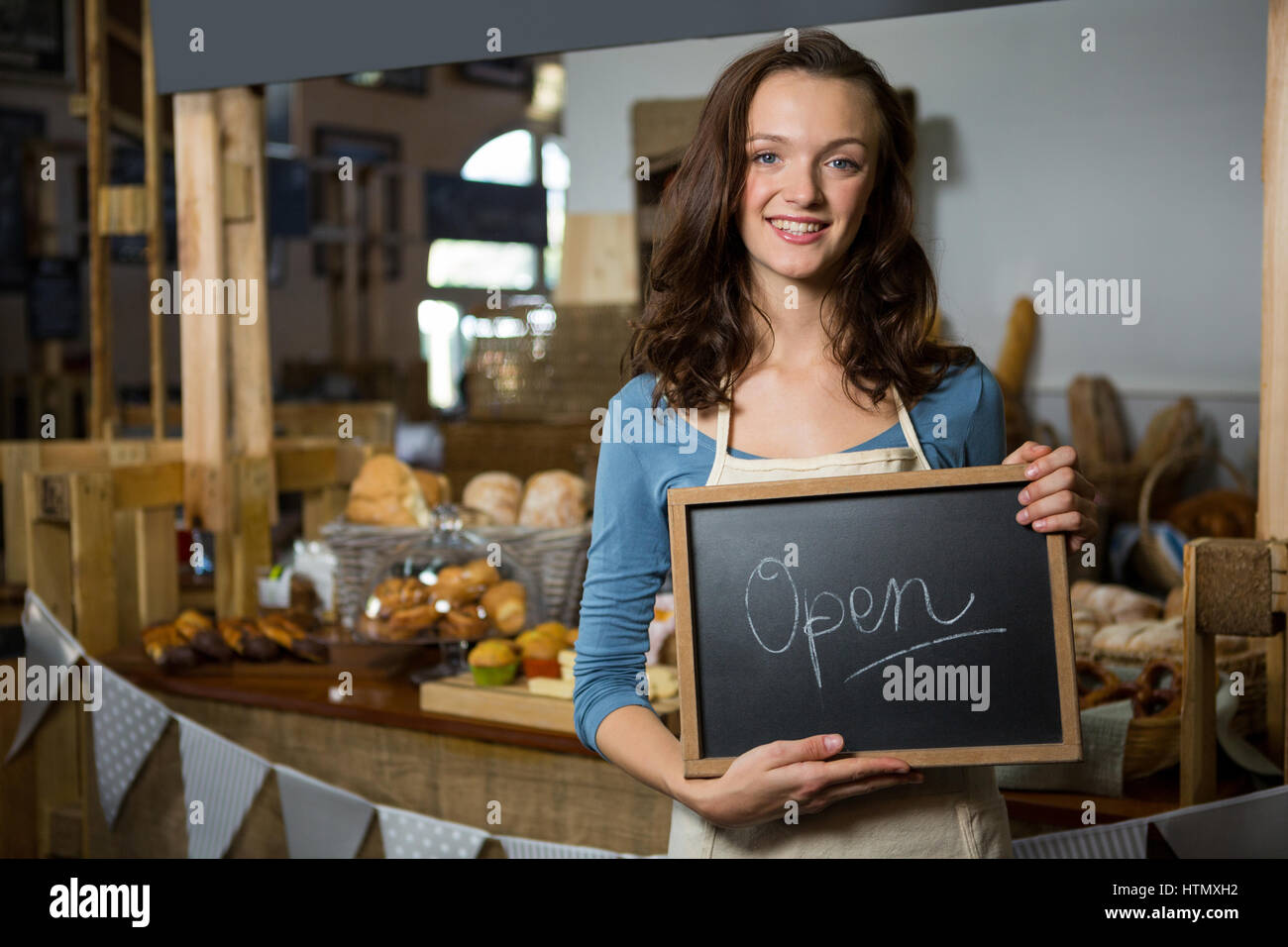 Portrait of a female staff holding a open sign in supermarket Stock Photo