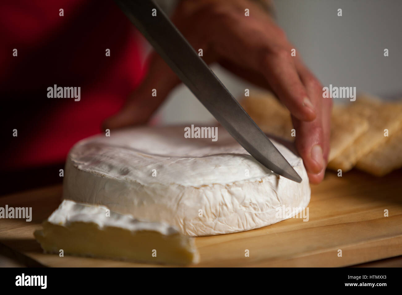 Hand of staff cutting cheese at counter in market Stock Photo