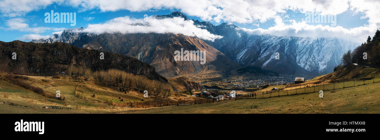 Panoramic view of the of Kazbegi Stepantsminda village and Gergeti village against Caucasus mountains. Georgia. Stock Photo