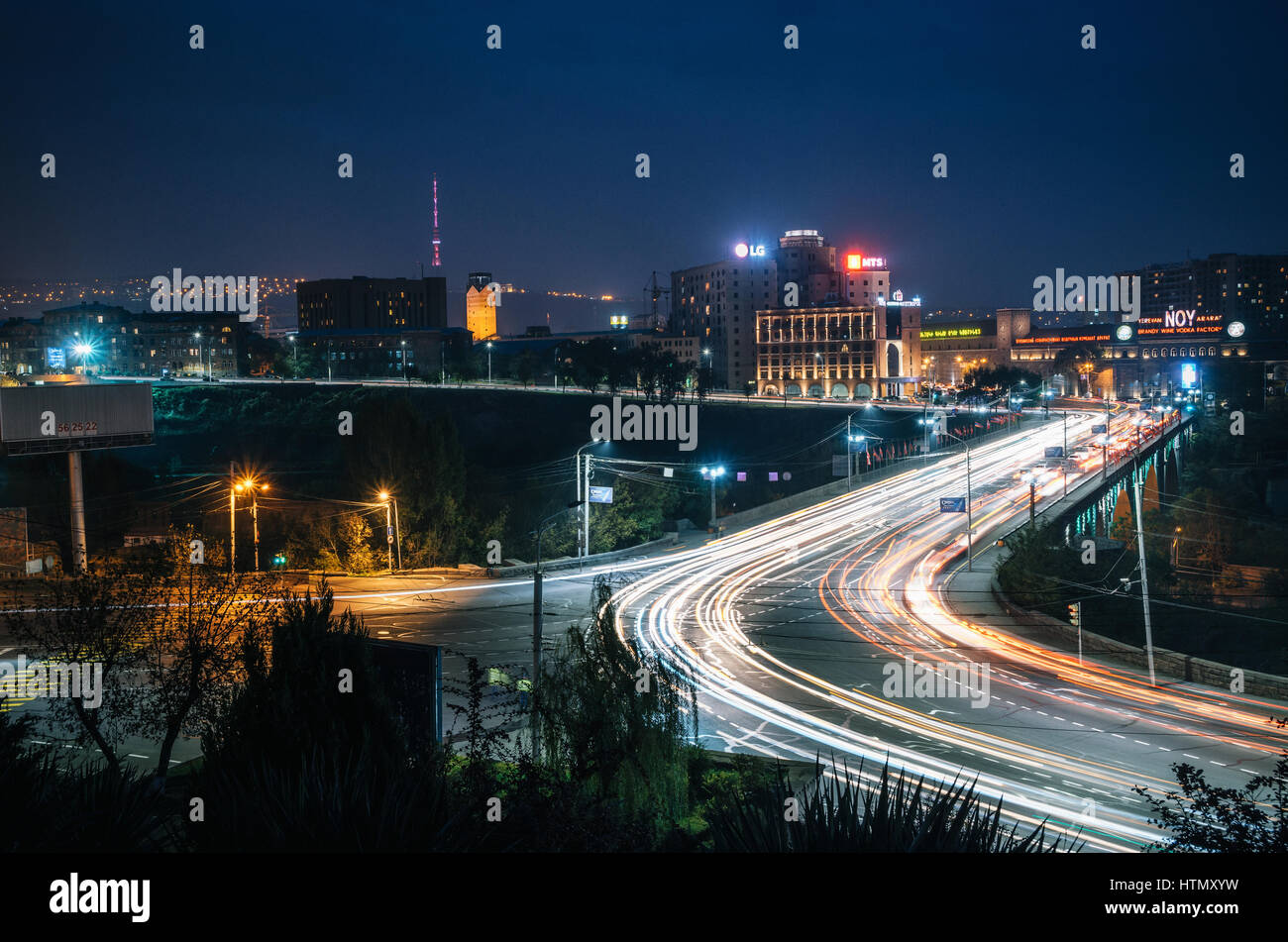 Yerevan, Armenia - October 24, 2016: Night view of The Victory Bridge or Haghtanak Bridge illuminated against Yerevan Ararat Brandy-Wine-Vodka Factory Stock Photo