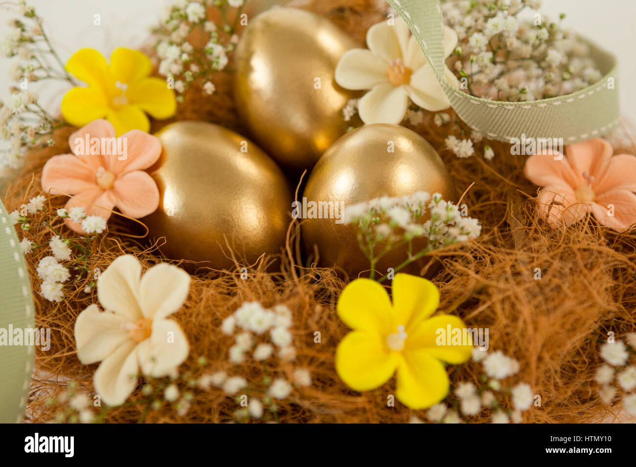 Golden easter eggs with flowers in nest against white background Stock ...