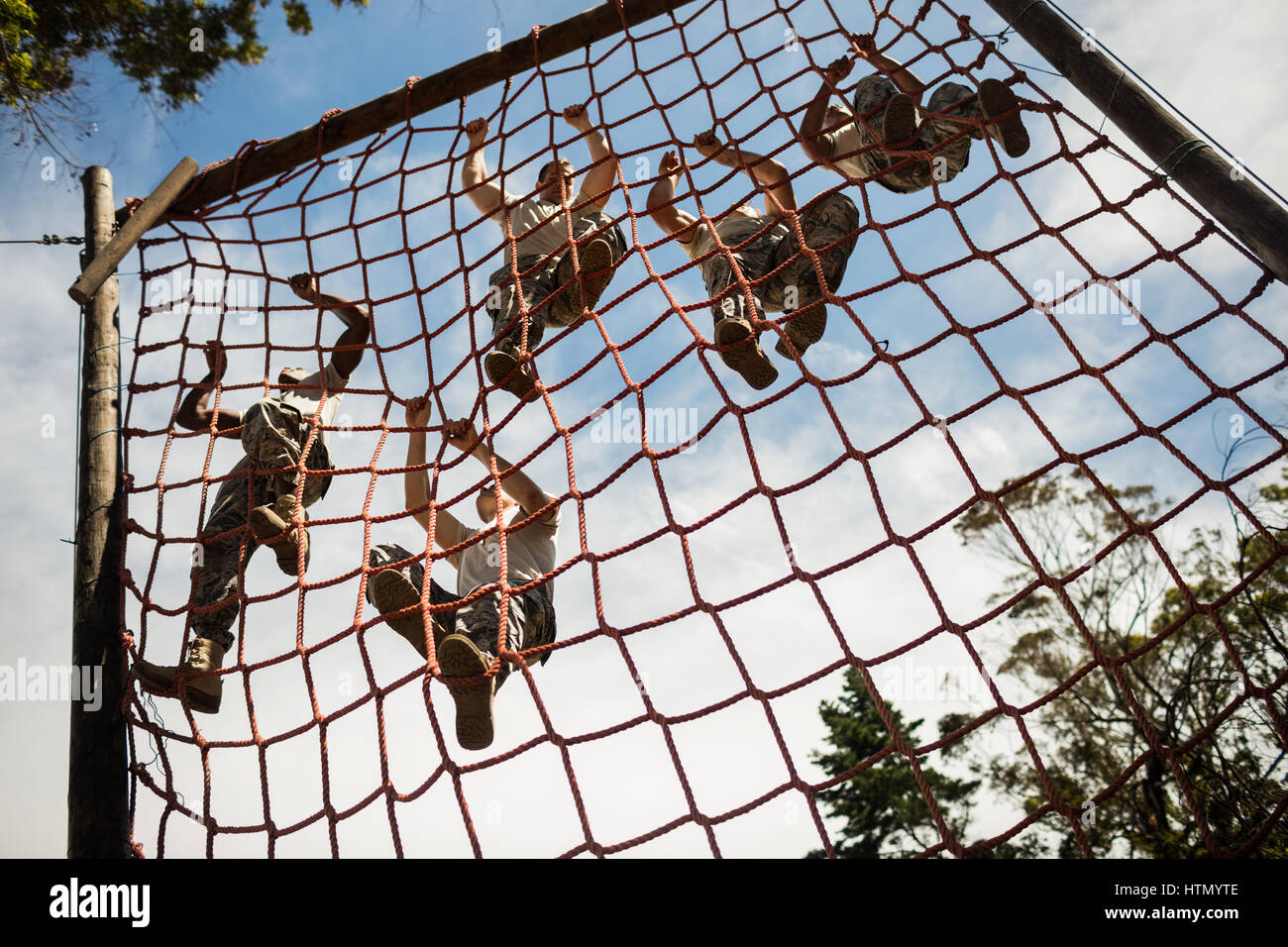 Military soldiers climbing rope during obstacle course in boot camp
