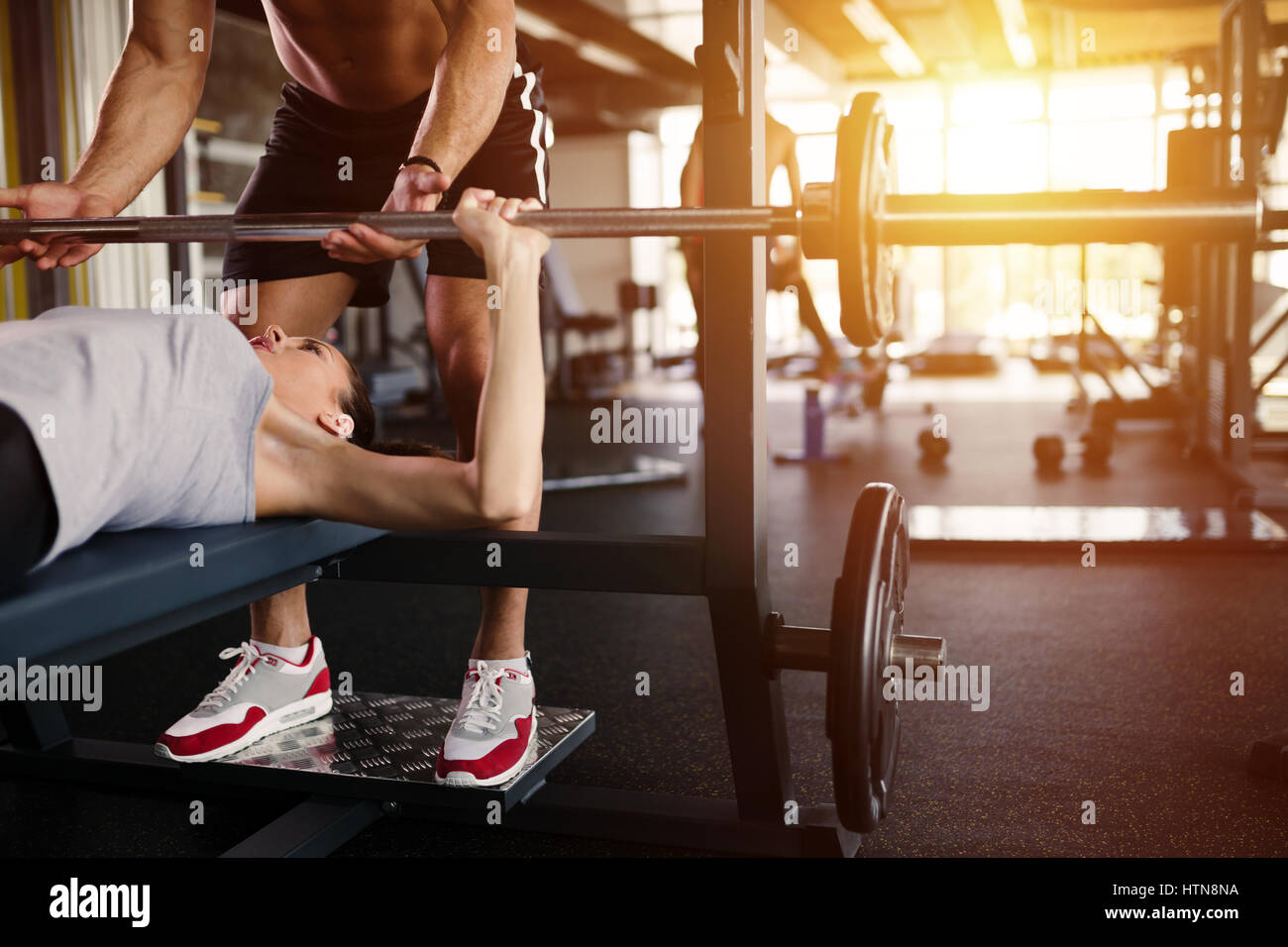 Personal trainer helping woman bench press in gym Stock Photo Alamy