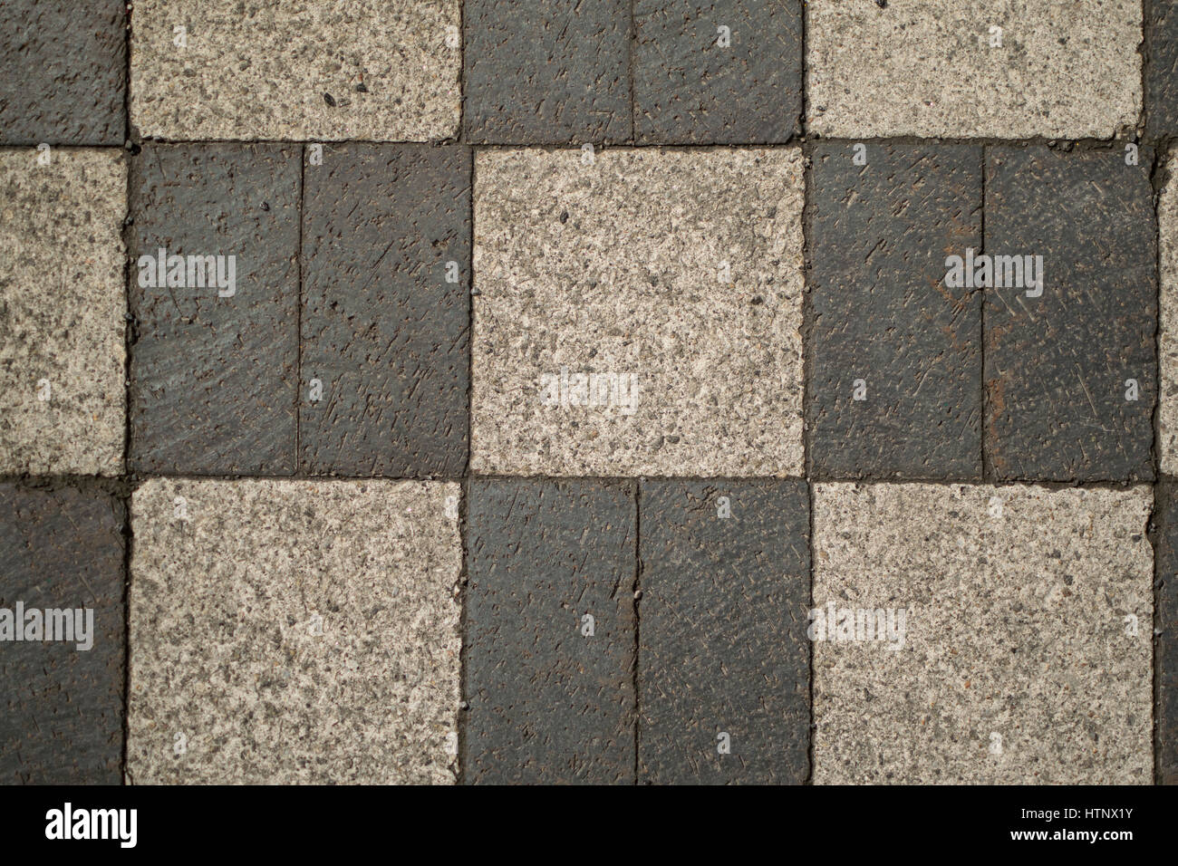Weathered dark and light gray brick sidewalk in a checkerboard pattern. Stock Photo