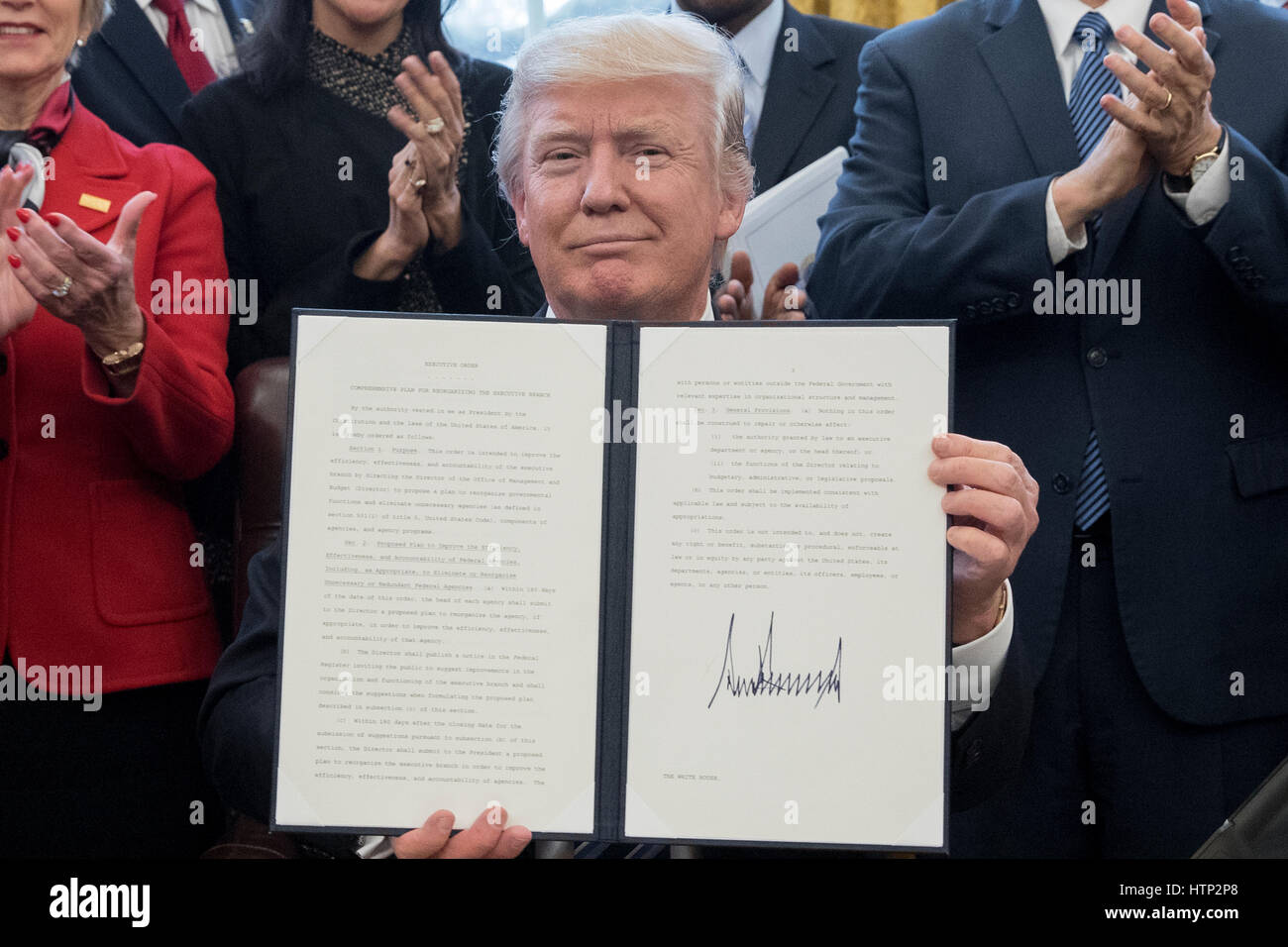 Washington DC, USA 13th March, 2017 US President Donald J Trump shows an executive order entitled, 'Comprehensive Plan for Reorganizing the Executive Branch', after signing it beside members of his Cabinet in the Oval Office of the White House in Washingt Stock Photo
