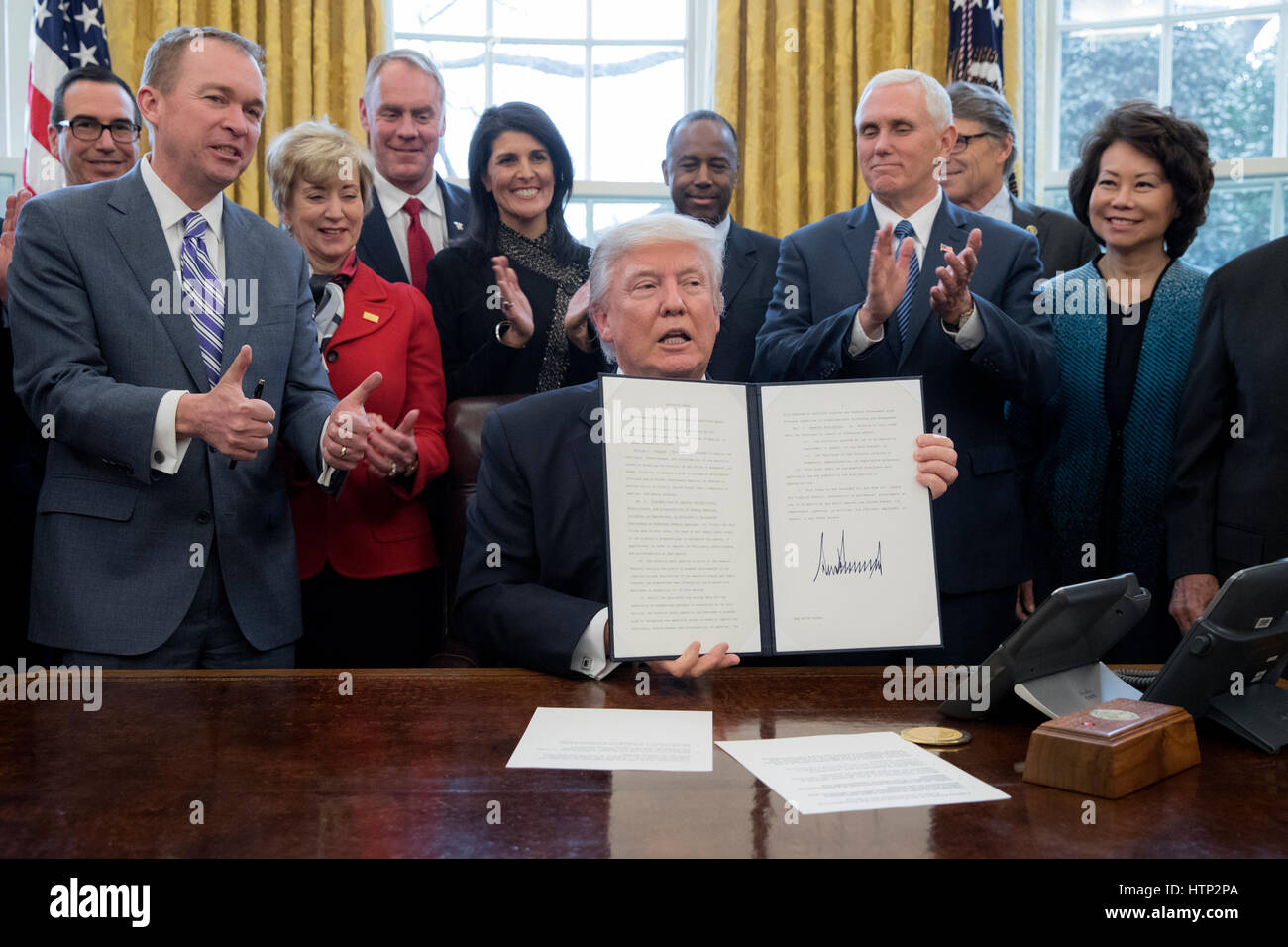 Washington DC, USA 13th March, 2017 US President Donald J Trump (C) shows an executive order entitled, 'Comprehensive Plan for Reorganizing the Executive Branch', after signing it beside members of his Cabinet in the Oval Office of the White House in Wash Stock Photo