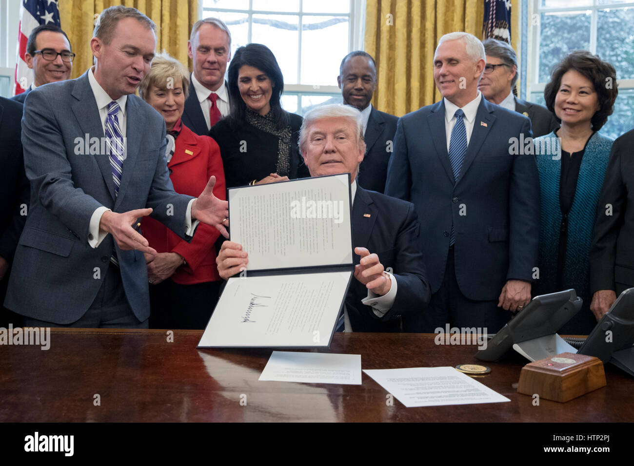 Washington DC, USA 13th March, 2017 US President Donald J Trump (C) shows an executive order entitled, 'Comprehensive Plan for Reorganizing the Executive Branch', after signing it beside members of his Cabinet in the Oval Office of the White House in Wash Stock Photo