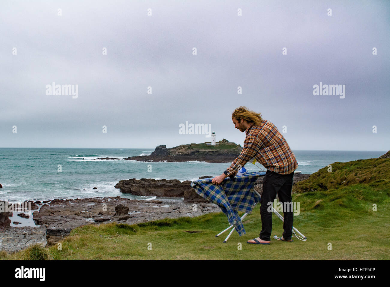 Gwithian, Cornwall, UK. 14th March 2017. UK Weather. Overcast with a breeze in Cornwall, with a threat of showers. Not ideal for washing your clothes, however James Chapman is an exponent of Extreme Ironing, and was out today dong his laundry on the Cornwall coast Credit: Simon Maycock/Alamy Live News Stock Photo