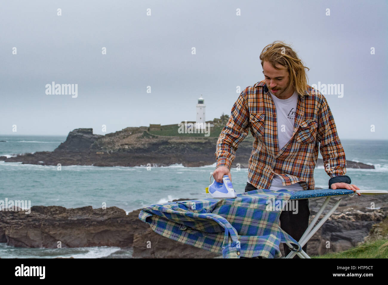Gwithian, Cornwall, UK. 14th March 2017. UK Weather. Overcast with a breeze in Cornwall, with a threat of showers. Not ideal for washing your clothes, however James Chapman is an exponent of Extreme Ironing, and was out today dong his laundry on the Cornwall coast Credit: Simon Maycock/Alamy Live News Stock Photo