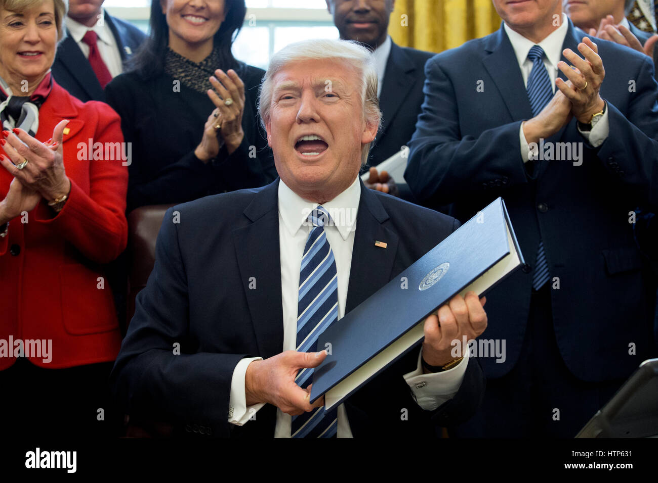 Washington, DC, USA. 13th Mar, 2017. US President Donald J. Trump (C) shows an executive order entitled, 'Comprehensive Plan for Reorganizing the Executive Branch', after signing it beside members of his Cabinet in the Oval Office of the White House in Washington, DC, USA, 13 March 2017. Credit: Michael Reynolds/Pool via CNP - NO WIRE SERVICE - Photo: Michael Reynolds/Consolidated News Photos/Michael Reynolds - Pool via CNP/dpa/Alamy Live News Stock Photo