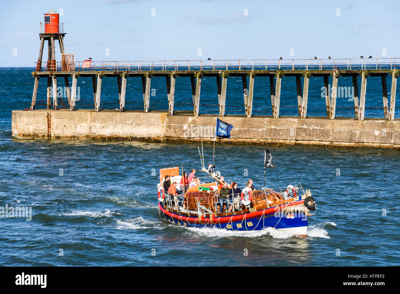 An RNLI lifeboat sightseeing boat enters the harbour at Whitby full of ...