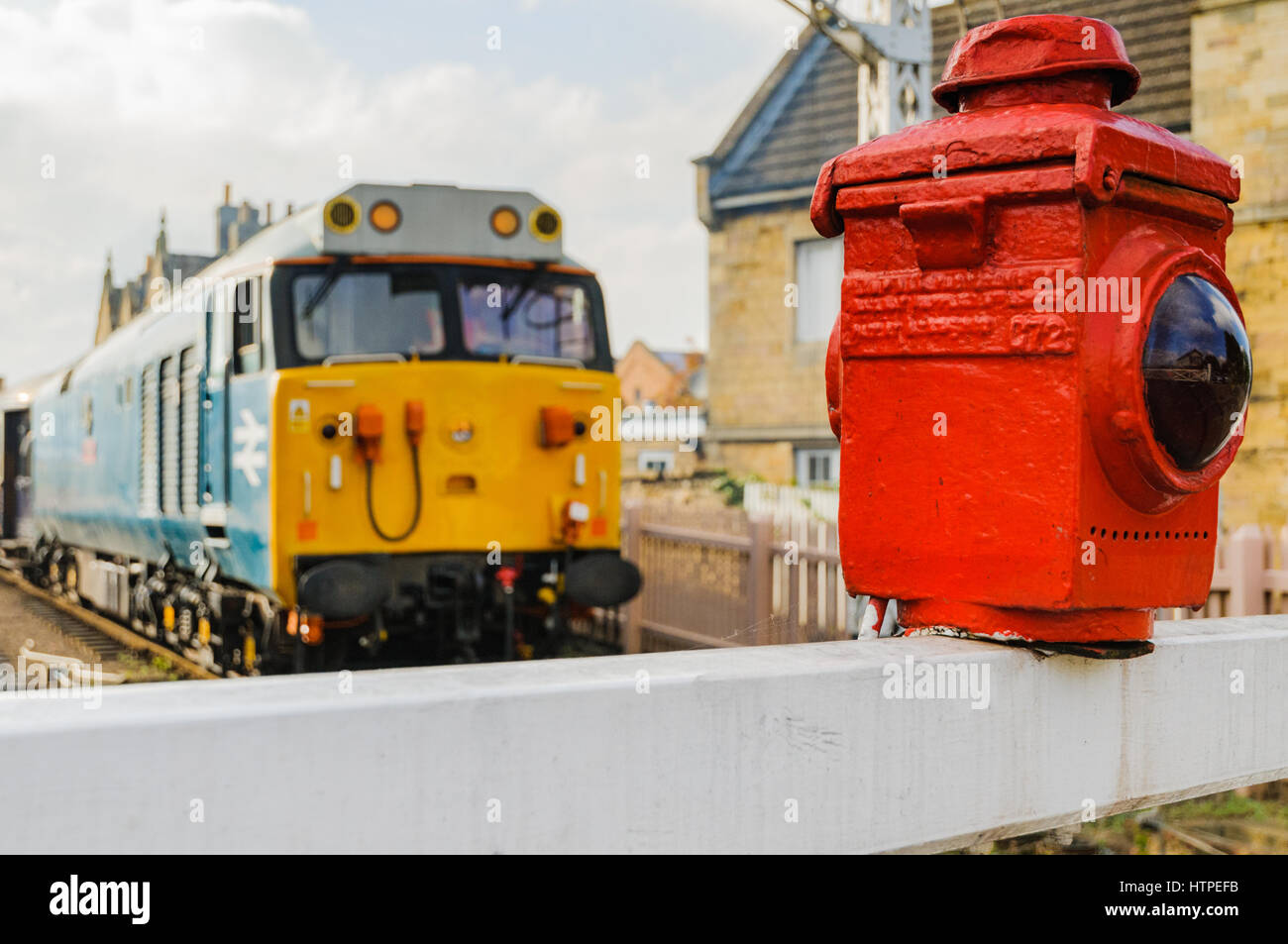 Warning lamp on a gated railway level crossing with a class 50 diesel loco in the background Stock Photo