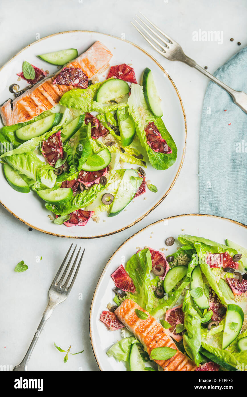 Healthy energy boosting spring salad with grilled salmon, blood orange, olives, cucumber and quinoa, top view, marble background. Clean eating, dietin Stock Photo