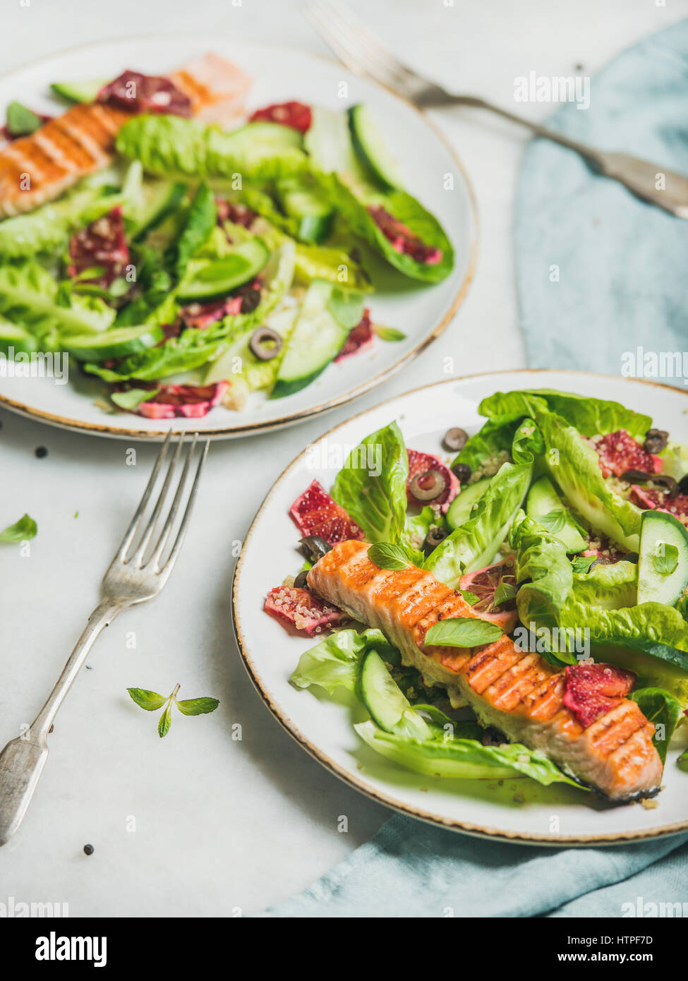Healthy energy boosting spring salad with grilled salmon, blood orange, olives, cucumber and quinoa over grey marble background, selective focus. Clea Stock Photo
