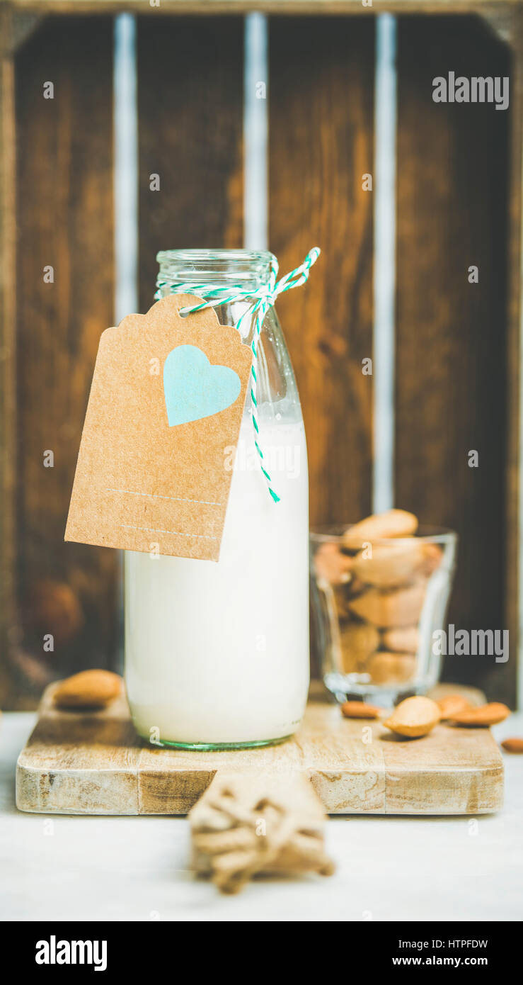 Fresh vegan dairy-free almond milk in glass bottle with craft paper label with copy space, wooden box at background. Vegan, vegetarian, raw, healthy, Stock Photo