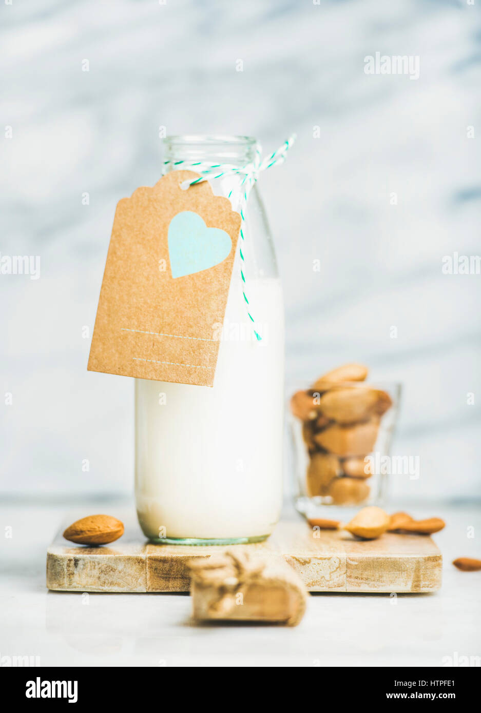 Fresh vegan dairy-free almond milk in glass bottle with craft paper label with copy space, grey marble background. Vegan, vegetarian, raw, healthy, cl Stock Photo