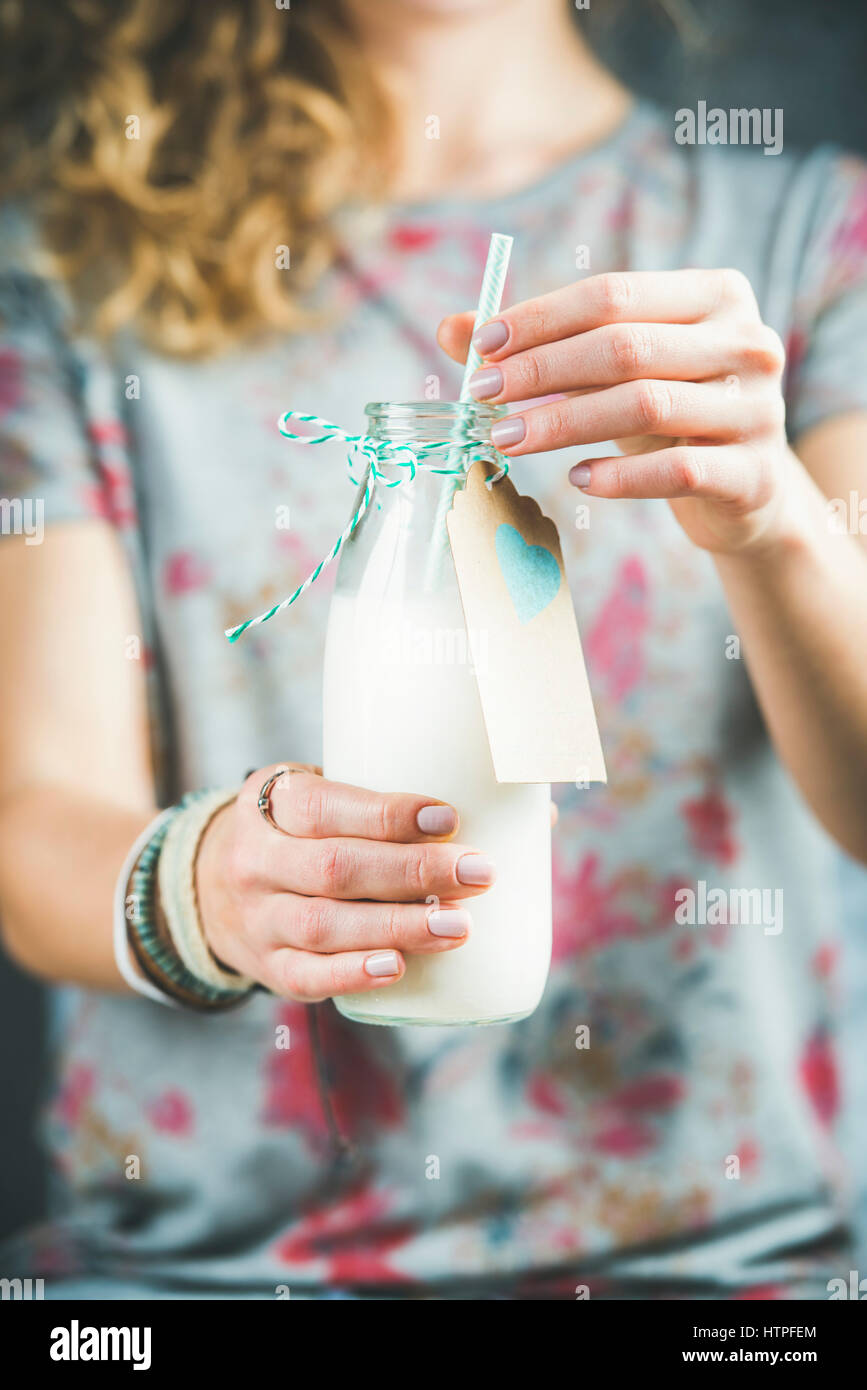 Young woman in grey t-shirt holding bottle of dairy-free almond milk in her hands. Clean eating, vegan, vegetarian, dieting, healthy food concept Stock Photo