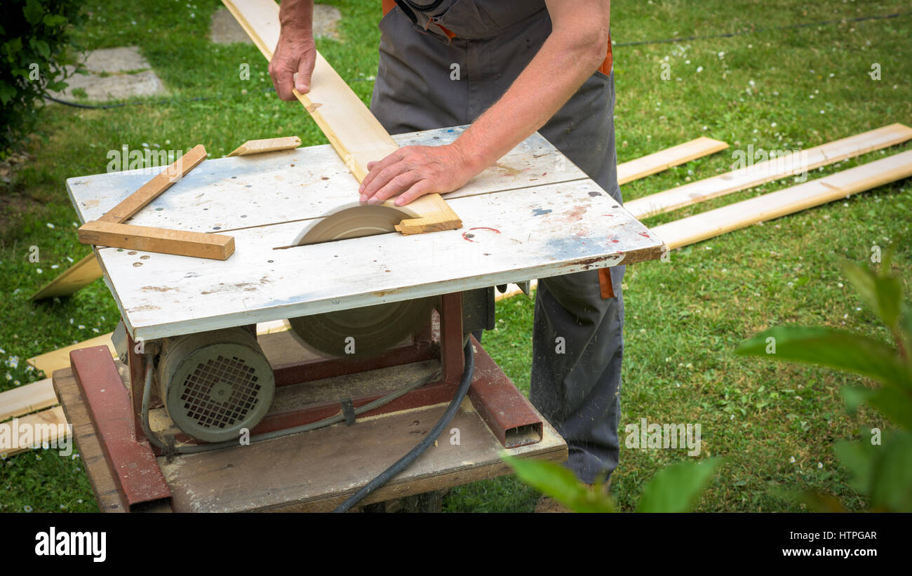 Carpenter working with electric buzz saw cutting wooden boards Stock Photo