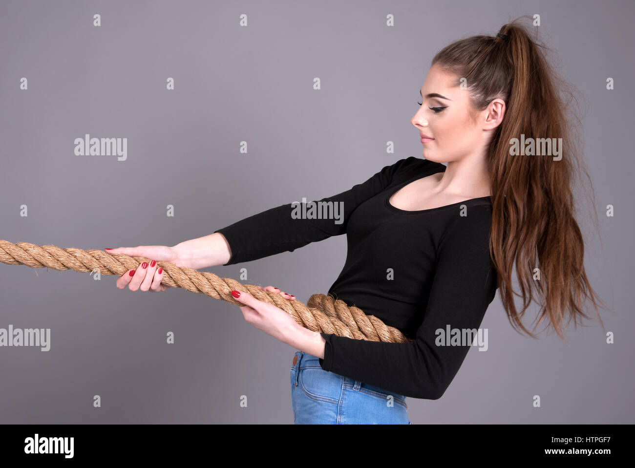 Young girl pulling on a rope Stock Photo