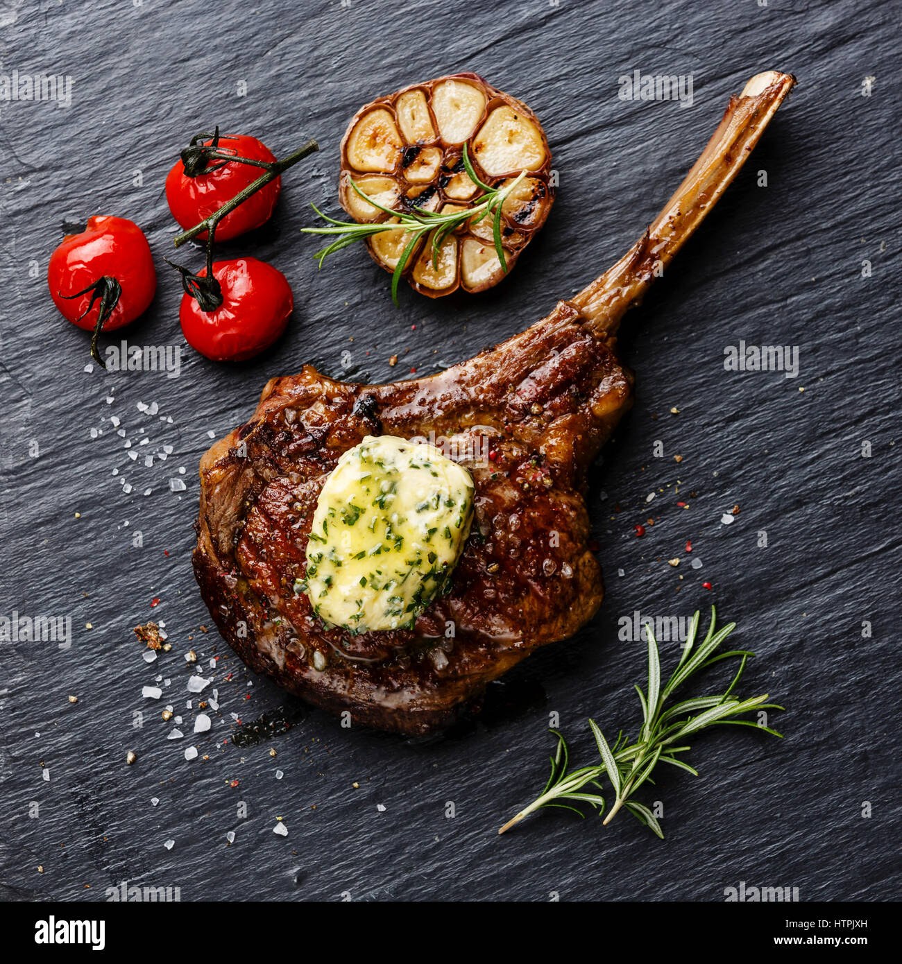 Grilled Steak on bone Veal rib with herb butter on stone slate background Stock Photo