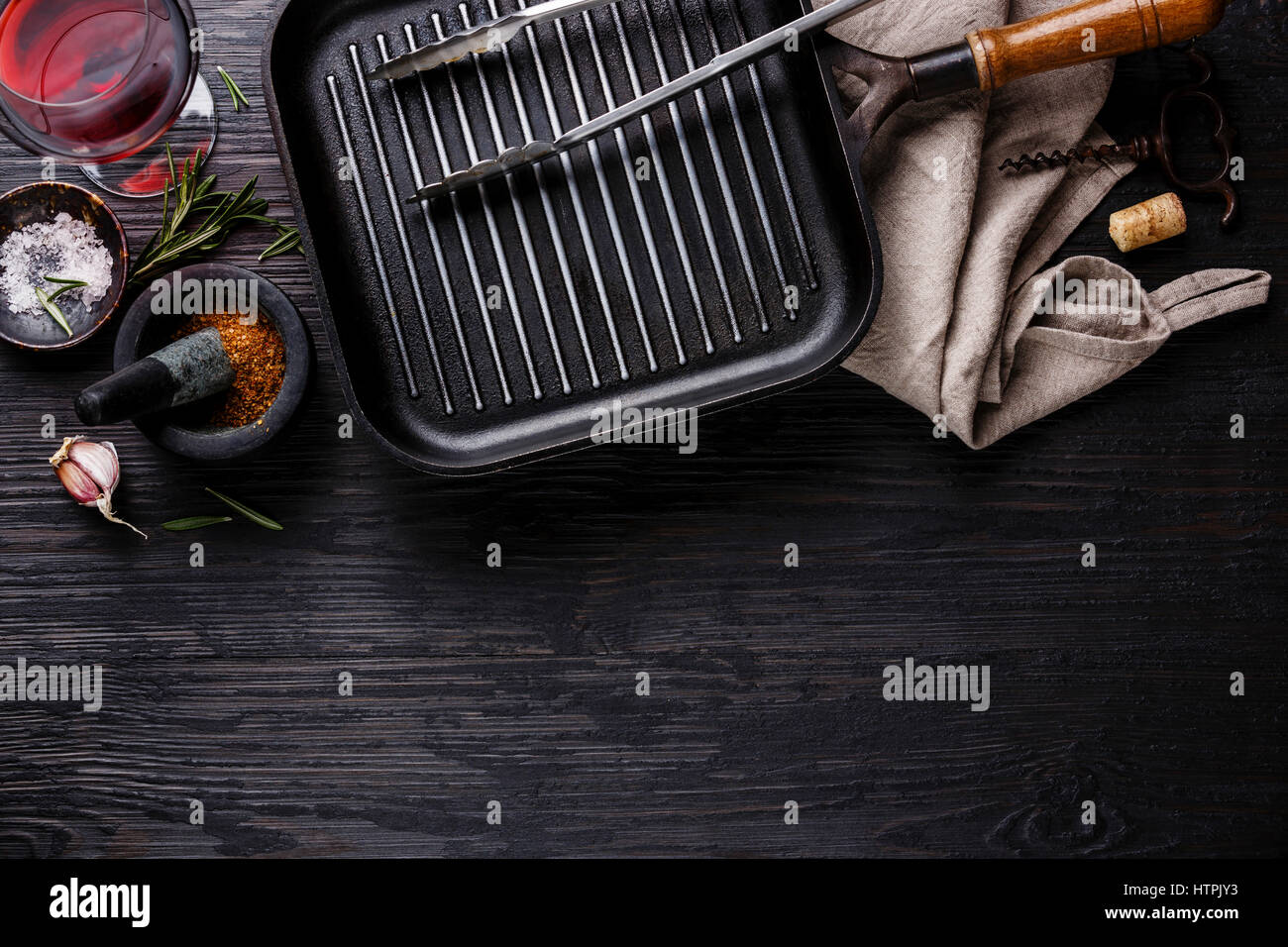 Empty frying pan, seasonings and red wine on black burned wooden background copy space Stock Photo