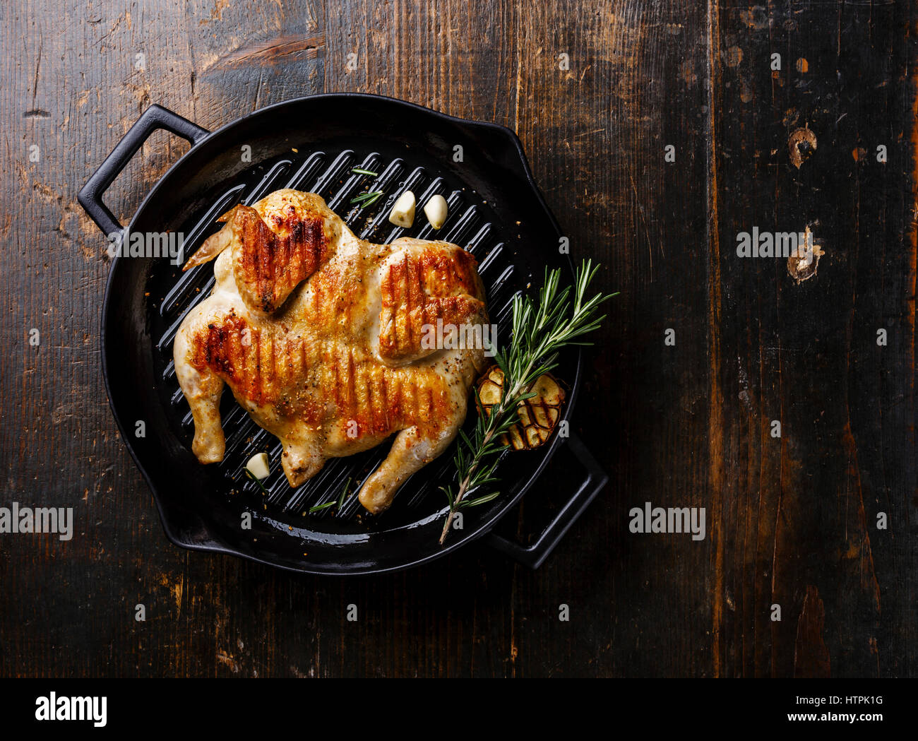 Grilled fried roast Chicken Tabaka in frying pan on wooden background copy space Stock Photo