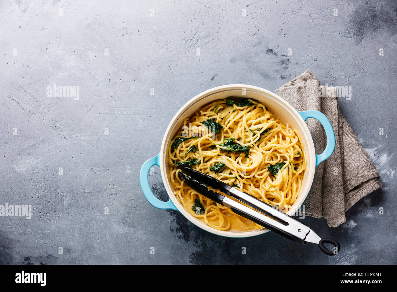 Spaghetti with Spinach and cream sauce in pan on gray concrete background copy space Stock Photo