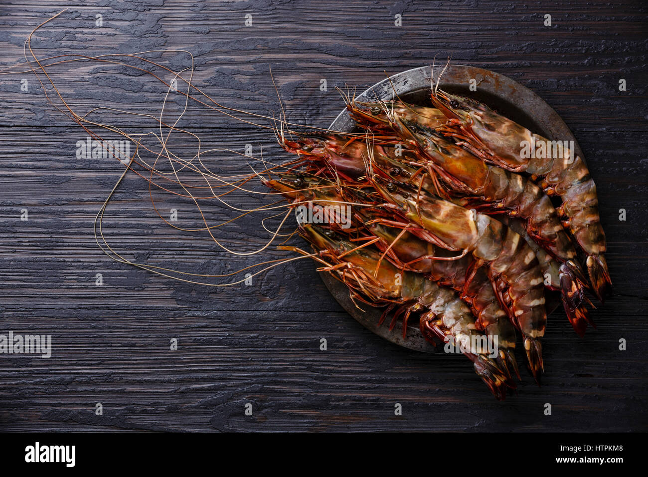Raw fresh Tiger Prawn Shrimp in metal plate on burned black wooden background Stock Photo