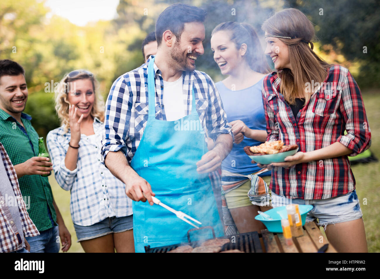 Happy friends grilling meat and enjoying barbecue party outdoors Stock ...