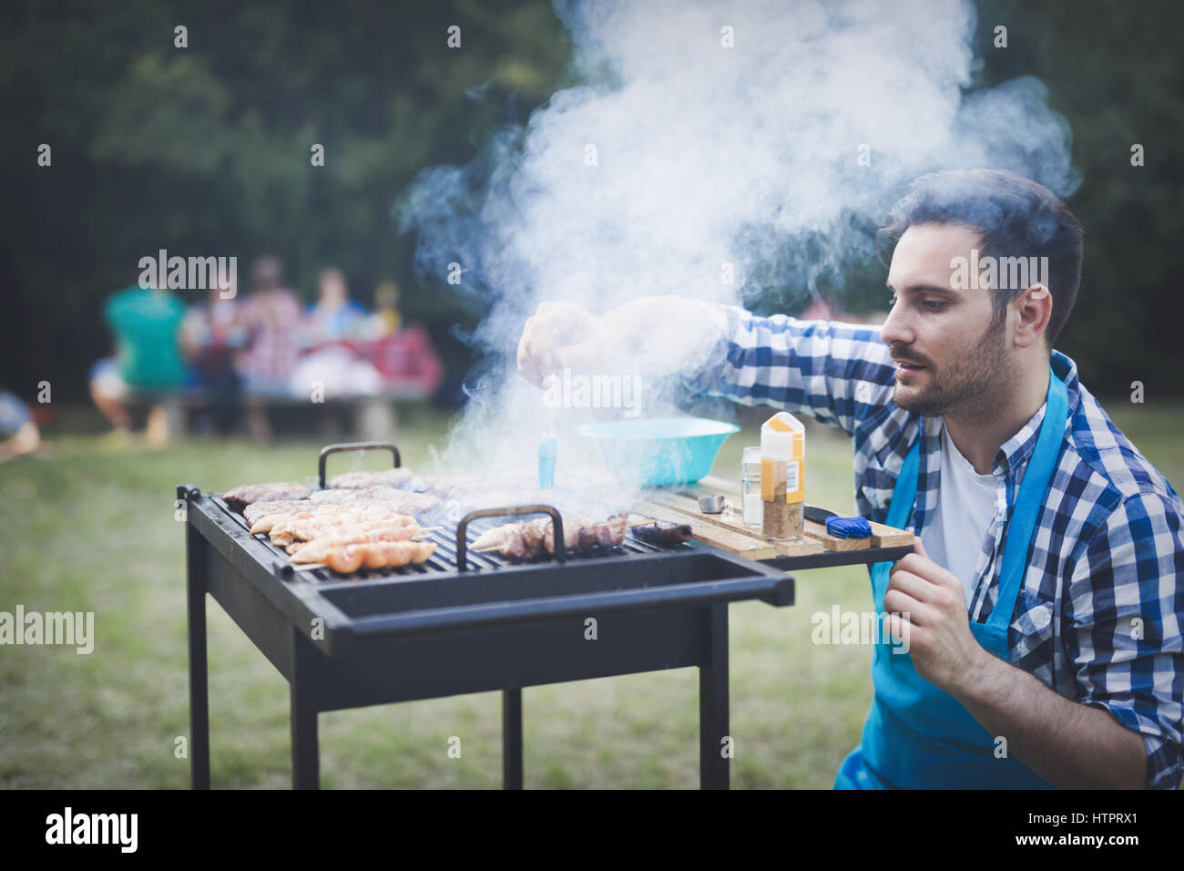 Happy male grilling bbq meat outdoor in nature Stock Photo