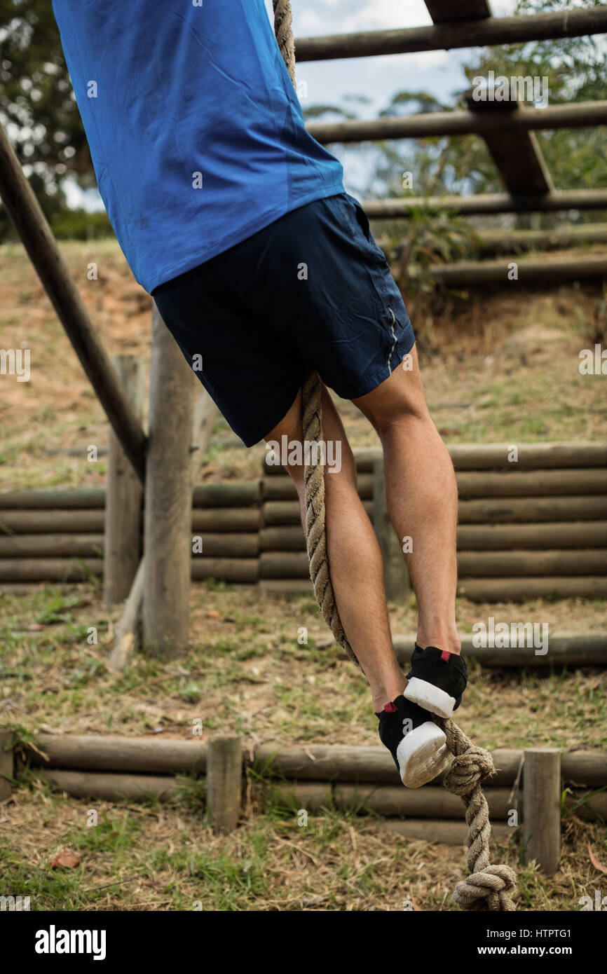 Low section of man climbing a rope during obstacle course in boot camp ...