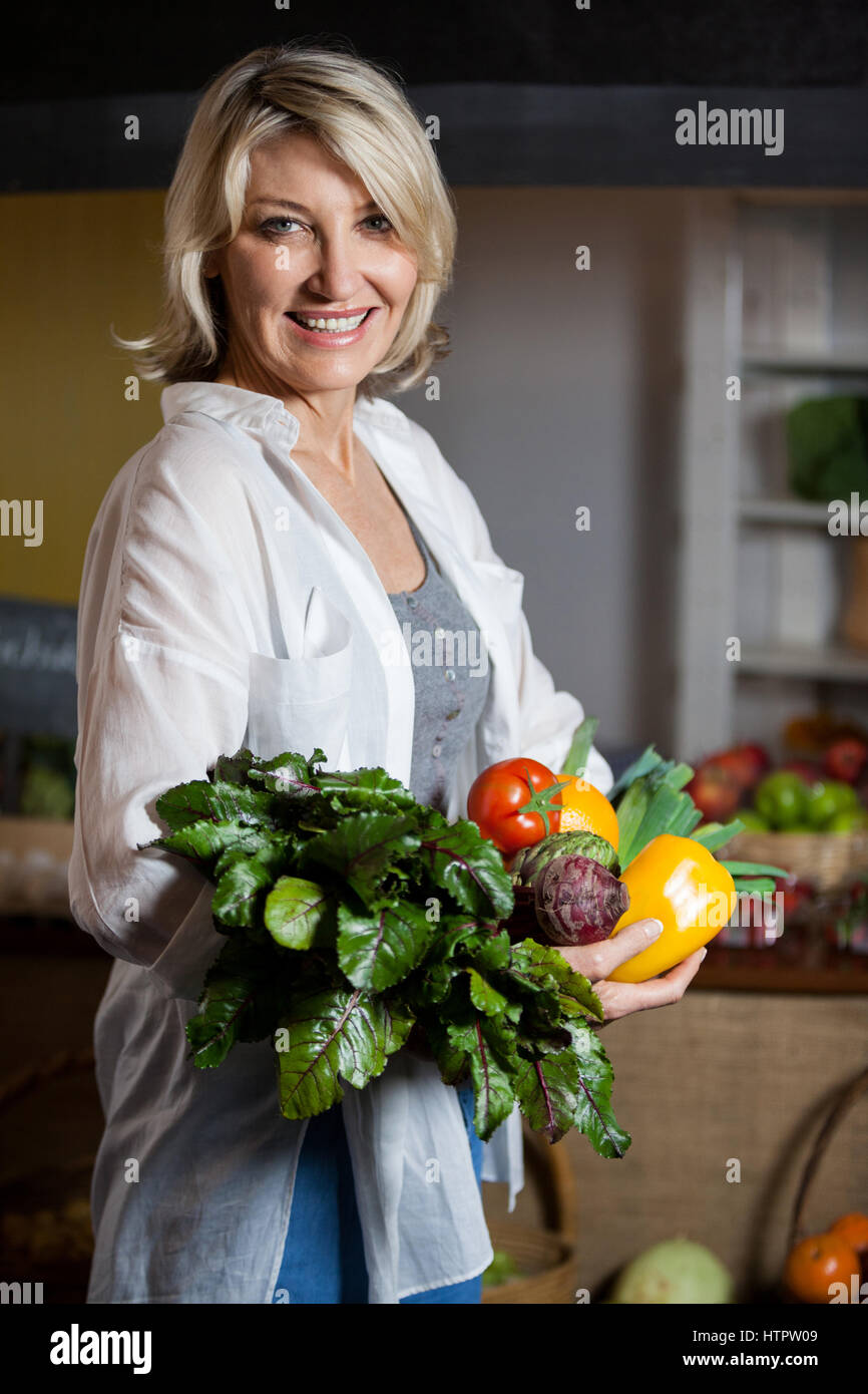 Portrait female costumer holding fresh vegetables and fruits in organic ...