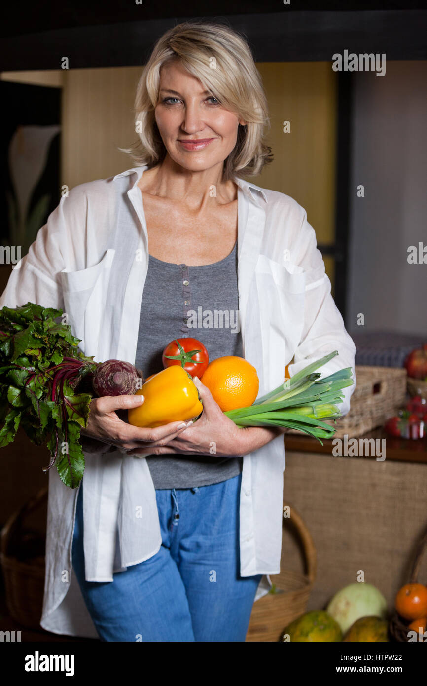 Portrait female costumer holding fresh vegetables and fruits in organic ...