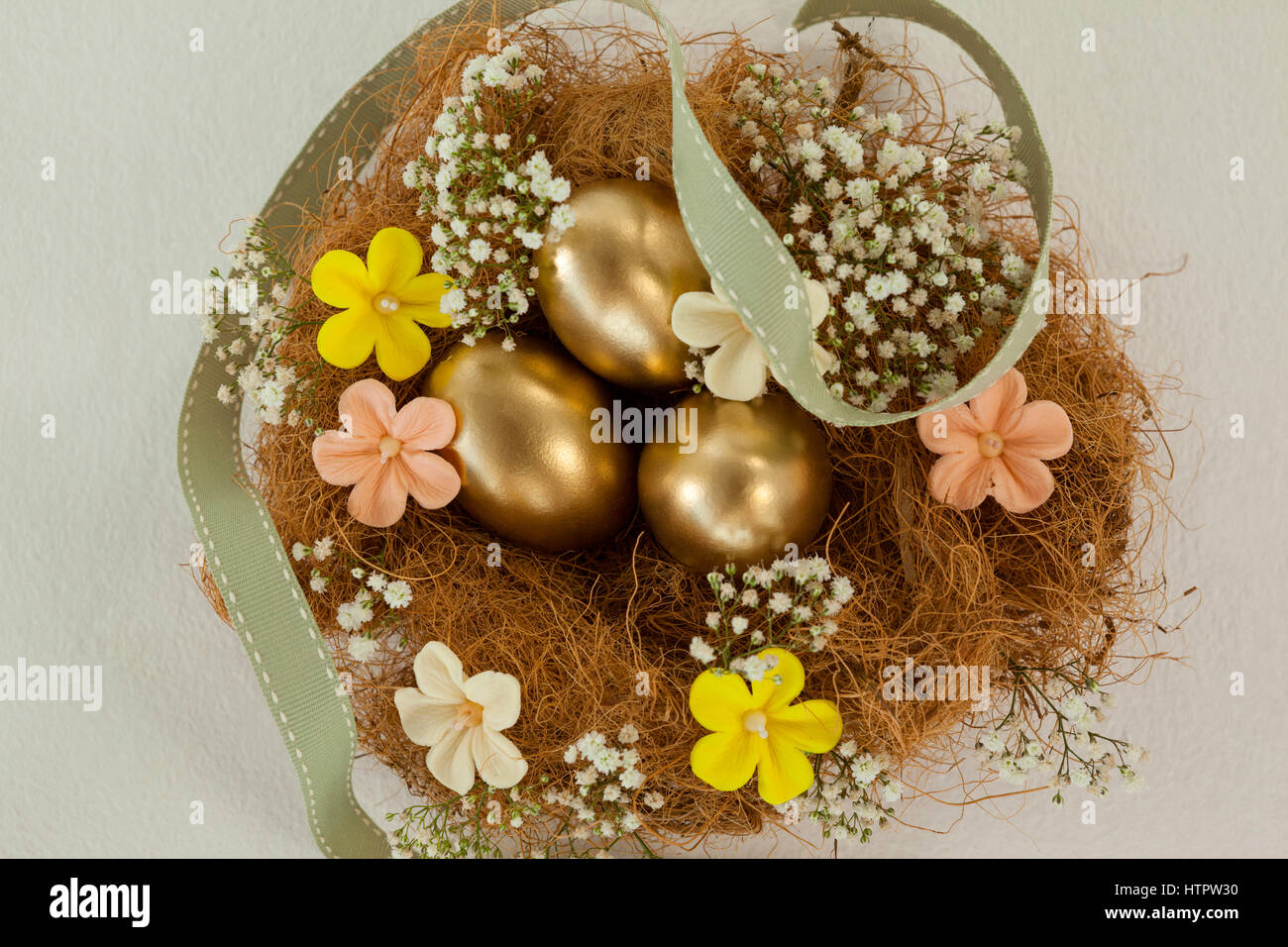 Golden easter eggs with flowers in nest against white background Stock ...