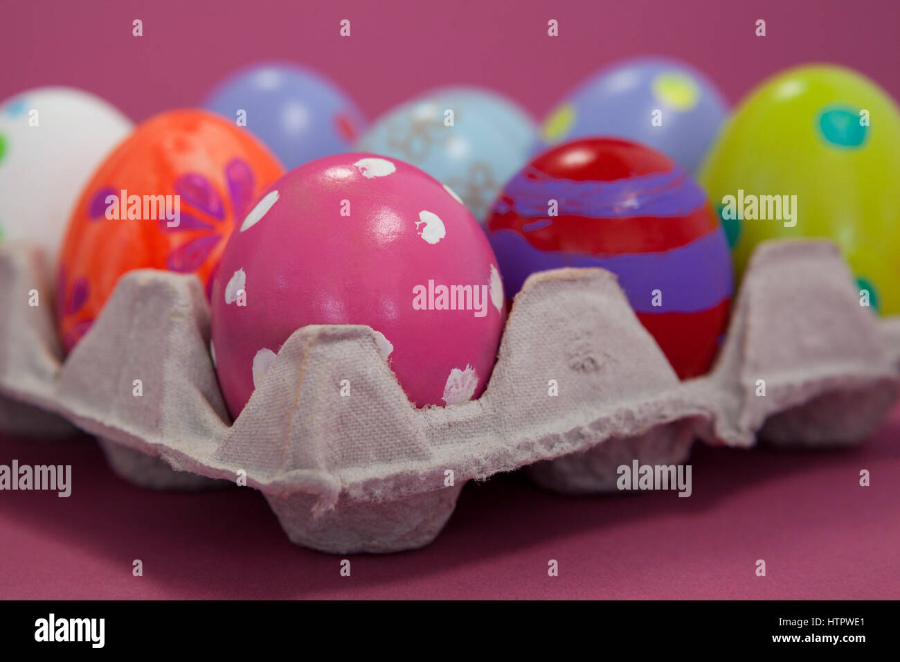 Colorful Easter eggs in egg carton on pink background Stock Photo - Alamy
