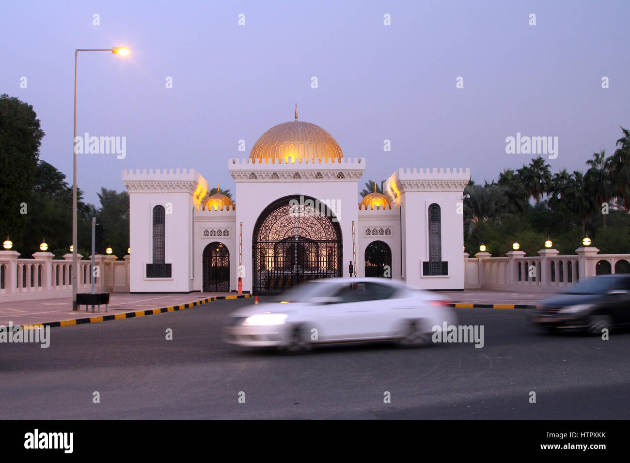 Cars drive past the entrance to the Al Qudaibiya Palace in the evening light, in the Gudaibiya district of Manama, Bahrain. Stock Photo