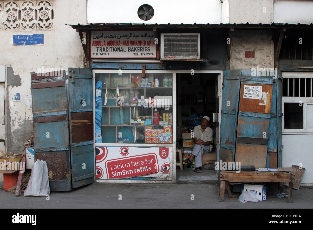 A shopkeeper stares out the door into the street, in central Manama, Bahrain Stock Photo