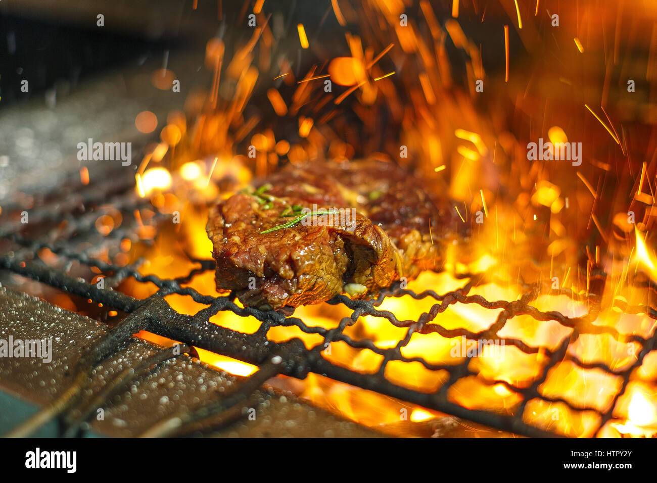 Beef steaks on the grill with flames. Grilled meat in barbecue with ...