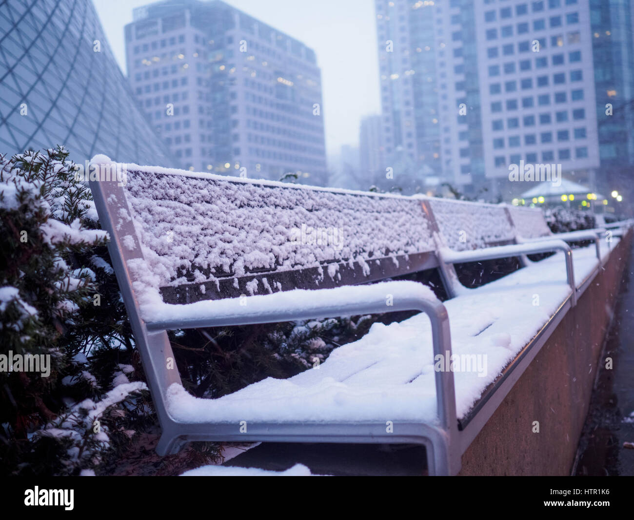 Empty bench seat covered with fresh snow in a city downtown Stock Photo