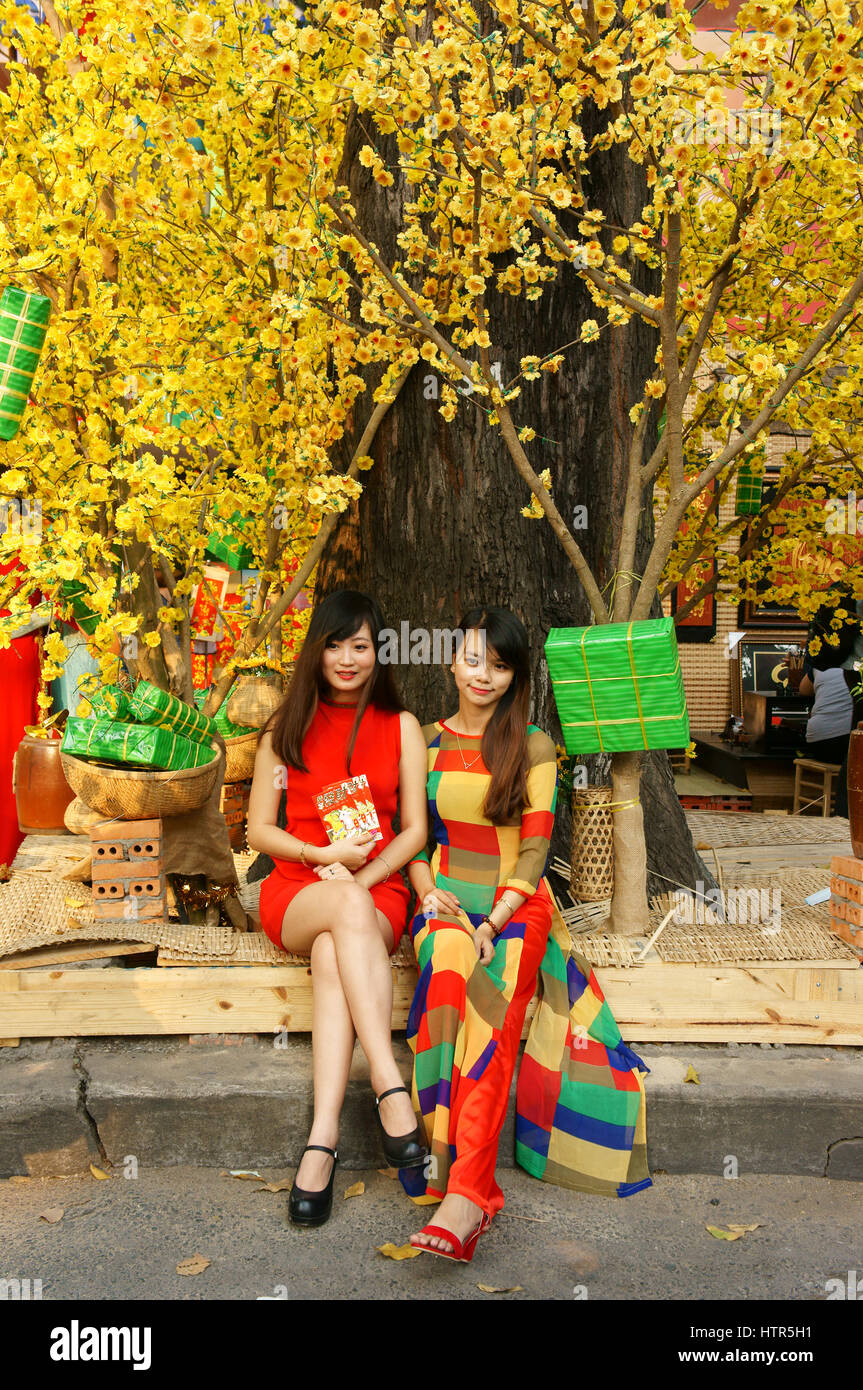 Ho Chi Minh city, Vietnam in springtime with colorful scene on Saigon street, Vietnamese woman in ao dai, posing beside flower to take photo on Tet Stock Photo
