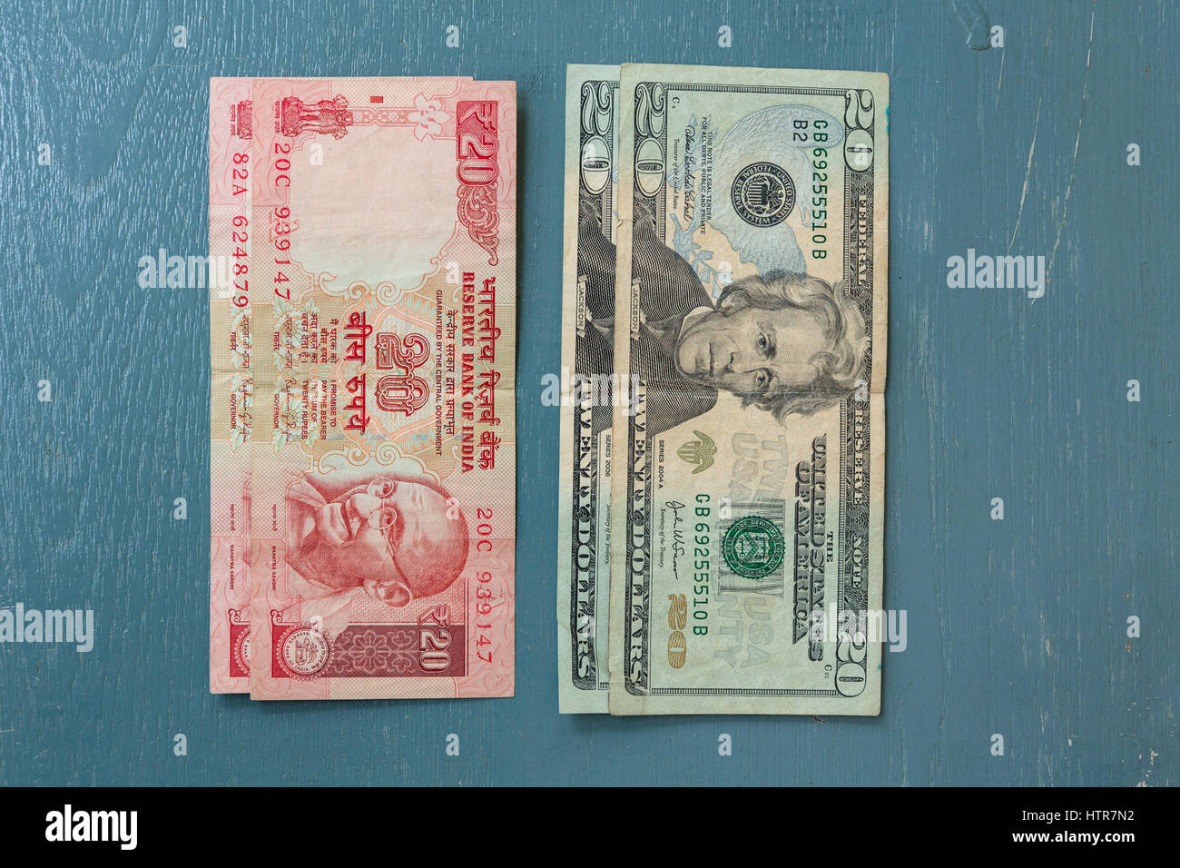 Close-up of Indian 20 Rupee Note and American 20 Dollar bill on plain background Stock Photo