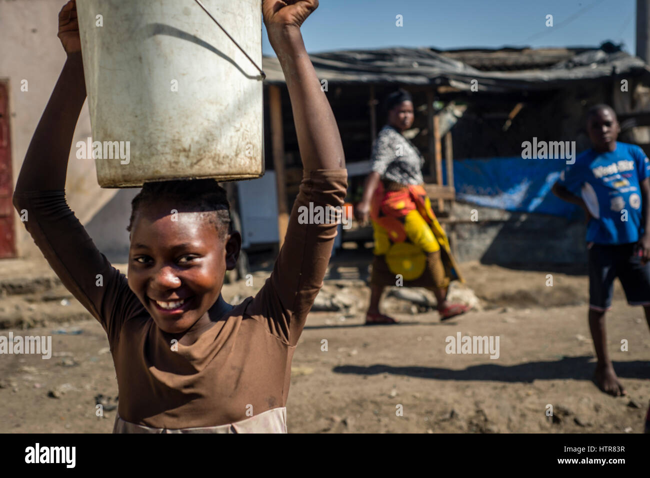 A girl walking at the market carrying bucket in her head, Lusaka, Zambia. Stock Photo