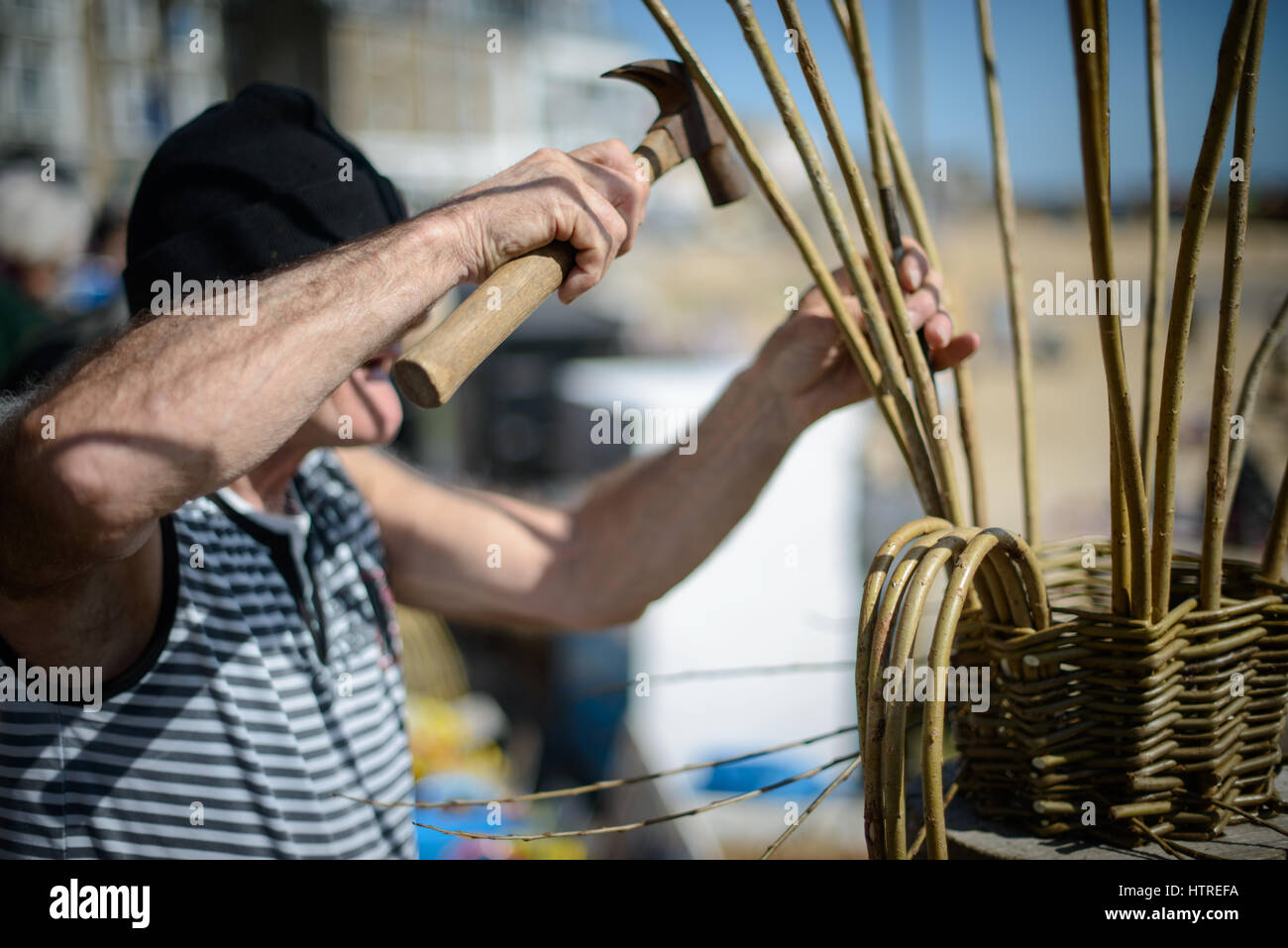 A man makes traditional cornish willow lobster pots called Withy Pots on the quayside of the harbour at St Ives, Cornwall, England, UK. Stock Photo