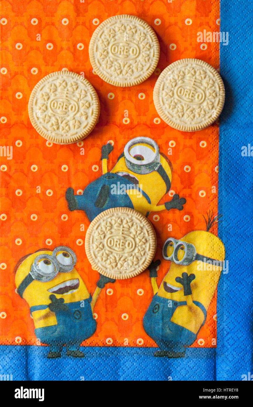 Golden Oreo biscuits on serviette with Minions - Minions juggling with Golden Oreo biscuits, sandwich biscuits with a vanilla flavour filling Stock Photo