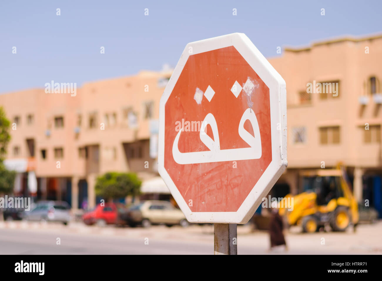 Image of a stop sign in focus and a blurred background whith arabic script in Morocco. Stock Photo