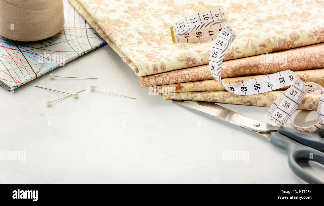 Accessories for sewing and cutting lie on a white table.  Space for an object. Stock Photo