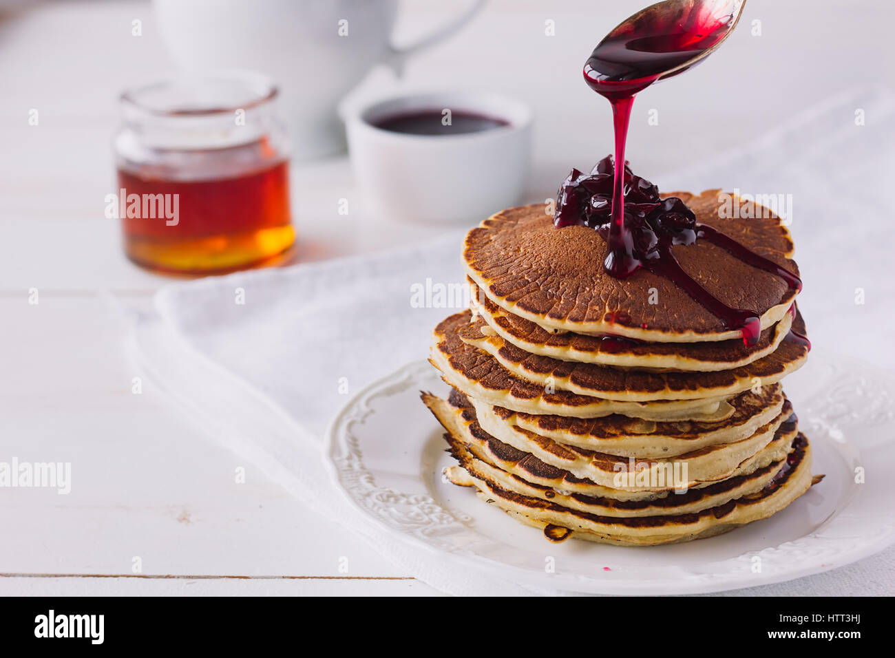 Pancakes with cherry jam on white dish selective focus Stock Photo