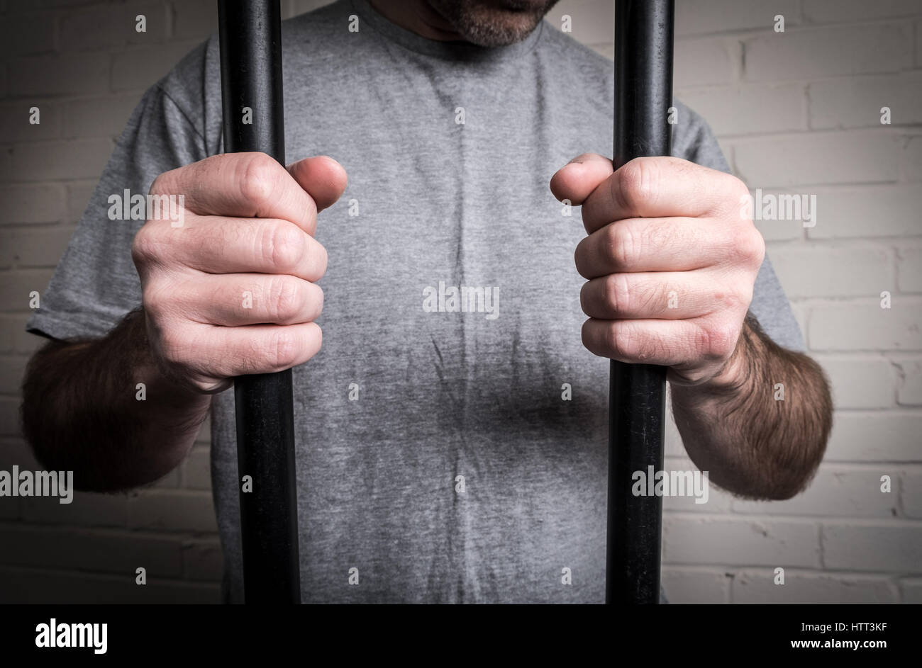A prisoner in his cell behind bars in prison. Picture posed by model Stock Photo