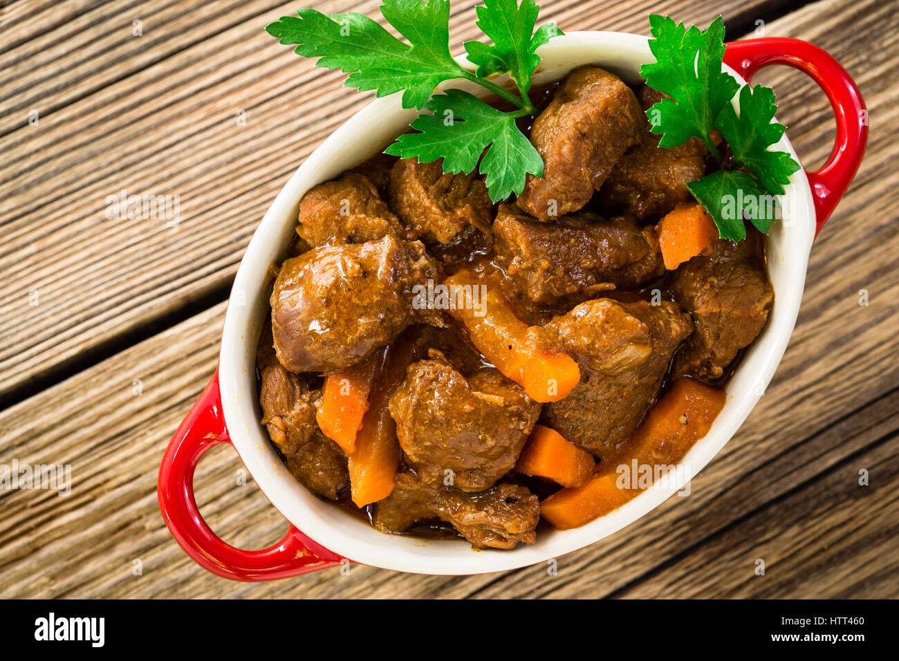 Beef stew with carrot. Traditional french beef goulash in red ceramic pot viewed from above